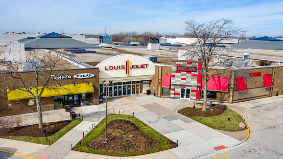 Joliet, IL, USA - April 8, 2019: A drone / aerial shot of a Louis Joliet Mall entrance with a Panera Bread and TGI Fridays on either side.