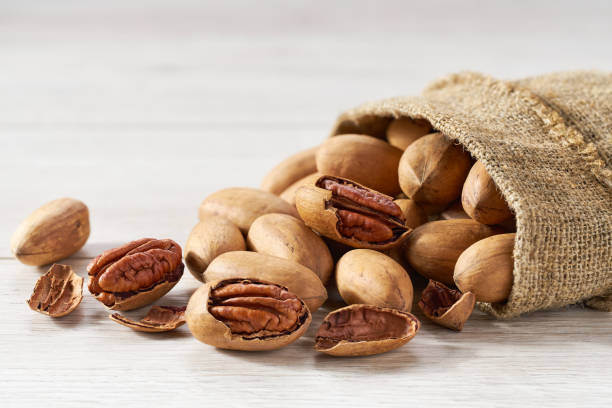 Pecan are poured out of the bag on a white  table, close-up. stock photo