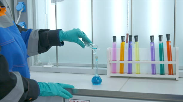 woman conducts laboratory experiments and analyzes. clip. woman looks at chemical liquid in laboratory. industrial laboratory with workers and chemicals in test tubes - impurities imagens e fotografias de stock