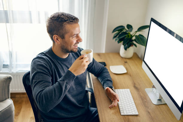 istock A young entrepreneur is drinking coffee and smiling at the computer at his home office. 1449845172