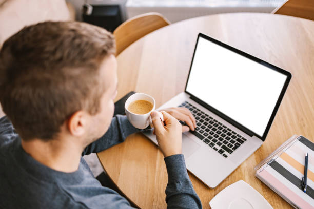 istock Back view of a man drinks coffee at home and researching internet. 1449845381
