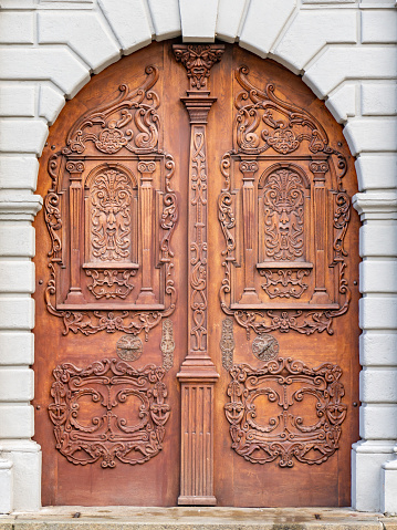 Ornate wooden door of Jesuit church in Bratislava, 17th century richly decorated arched gate