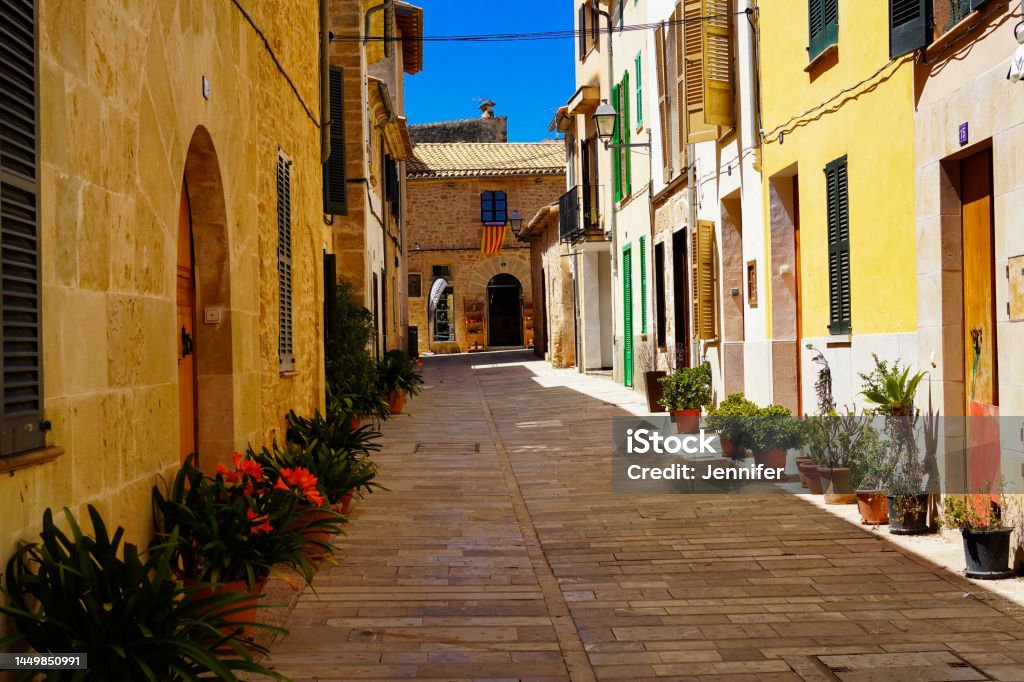 narrow street in the old town of Alcúdia, Mallorca in Spain Alley Stock Photo