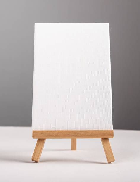 istock Vertical empty blank white canvas mock up standing on mini wood tripod on desk 1449853107