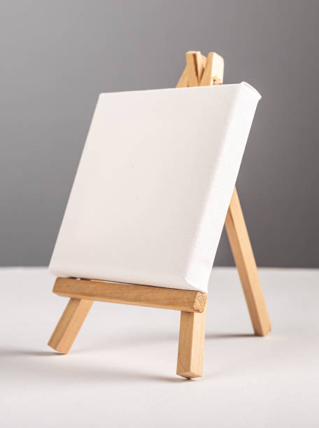 istock Empty blank white canvas mockup standing on mini wood tripod easel on desk 1449853108