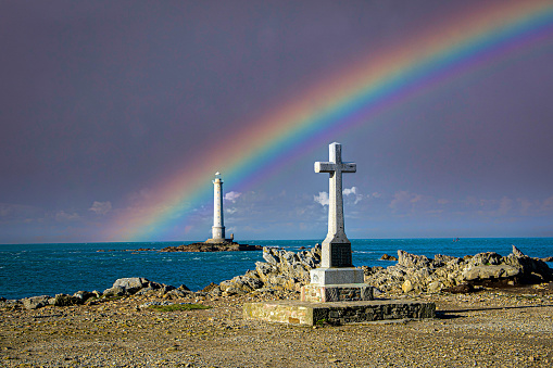 cross and lighthouse of la Hague under a rainbow