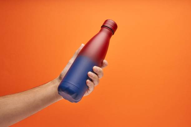 istock Hand holding a colorful thermal bottle on an orange background 1449861337
