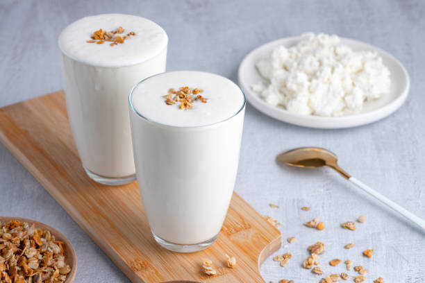 Kefir, buttermilk or yogurt, cottage cheese with granola. Yogurt in glass on white wooden background. Probiotic cold fermented dairy drink. Gut health, fermented products, healthy gut flora concept. Copy space. kéfir, suero de leche o yogur, requesón con granola. yogur en vaso sobre fondo de madera blanca. bebida láctea fermentada en frío probiótica. salud intestinal, productos fermentados, concepto de flora intestinal saludable. espacio de copia