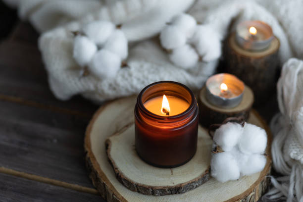 istock Cozy autumn or winter composition with aromatic candle, wool sweater, book. Aromatherapy, home atmosphere of cosiness and relax. Wooden background close up. 1449865719
