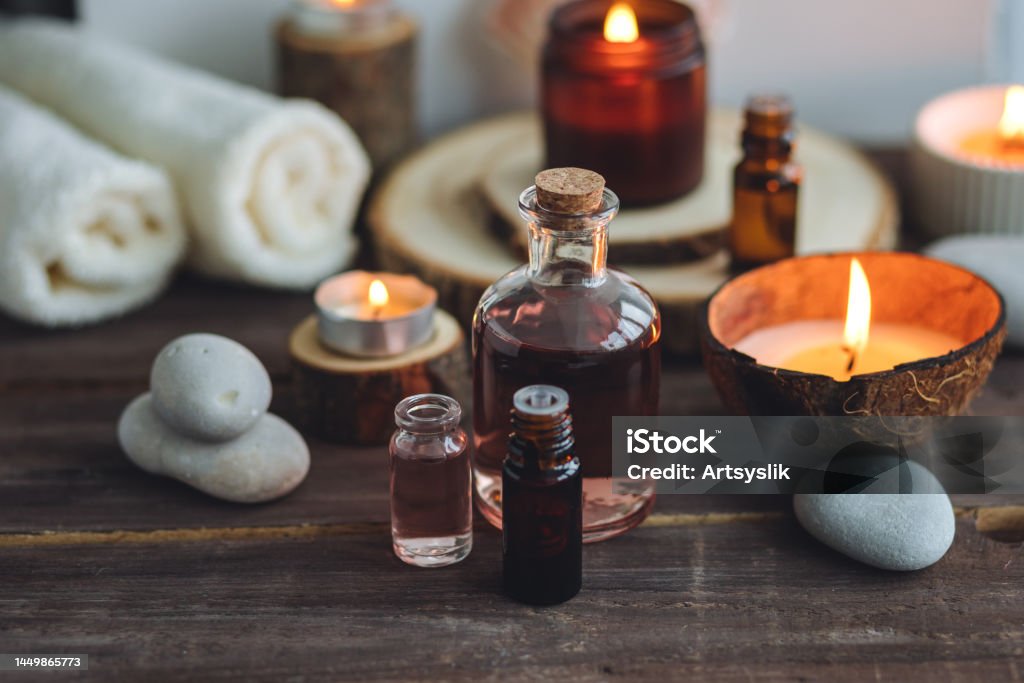 Concept of natural essential organic oils, Bali spa, beauty treatment, relax time. Atmosphere of relaxation, pleasure. Candles, towels, dark wooden background. Alternative oriental medicine Aromatherapy Diffuser Stock Photo