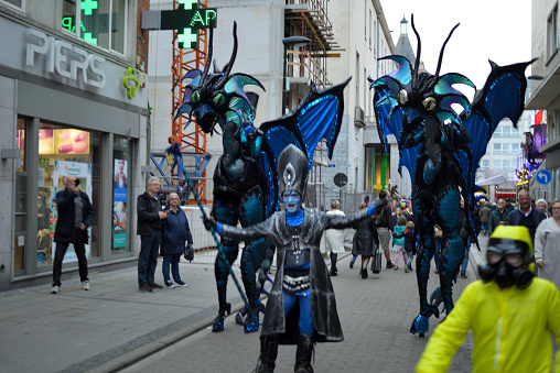 Oostend, West-Flanders, Belgium - October 31, 2022: motion blur,  make-up unrecognizable women in elf insects or demons clothes passing in shopping street