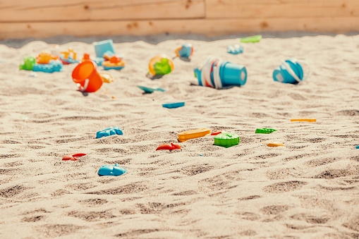 Toys are scattered in a large children's sandbox. Childhood and leisure of kids