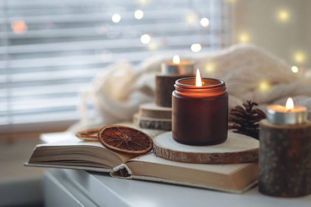 istock Cozy autumn or winter composition with aromatic candle, wool sweater, book. Aromatherapy, home atmosphere of cosiness and relax. Wooden background close up. 1449868876