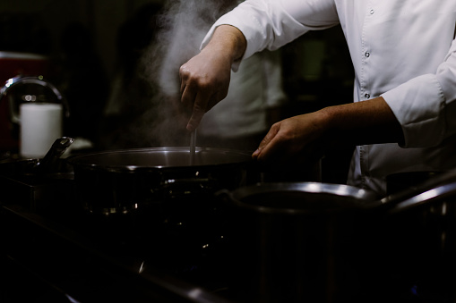 A cook stirring pots in the kitchen. Big pots in the kitchen. SELECTİVE FOCUS
