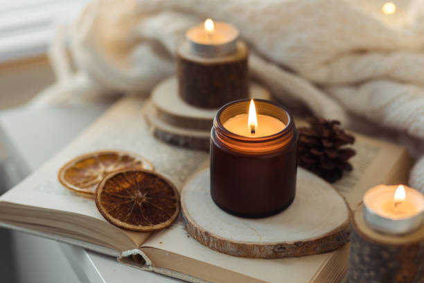 istock Cozy autumn or winter composition with aromatic candle, wool sweater, book. Aromatherapy, home atmosphere of cosiness and relax. Wooden background close up. 1449868884