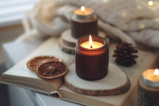 istock Cozy autumn or winter composition with aromatic candle, wool sweater, book. Aromatherapy, home atmosphere of cosiness and relax. Wooden background close up. 1449868886