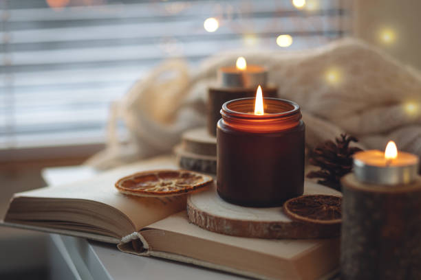istock Cozy autumn or winter composition with aromatic candle, wool sweater, book. Aromatherapy, home atmosphere of cosiness and relax. Wooden background close up. 1449868889