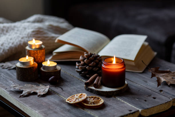 istock Cozy autumn or winter composition with aromatic candle, wool sweater, book. Aromatherapy, home atmosphere of cosiness and relax. Wooden background close up. 1449868894