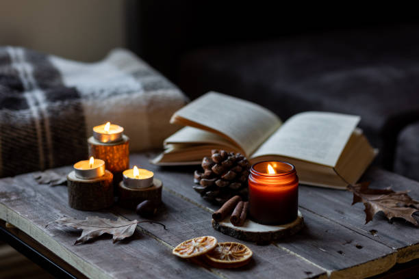 istock Cozy autumn or winter composition with aromatic candle, wool sweater, book. Aromatherapy, home atmosphere of cosiness and relax. Wooden background close up. 1449868895