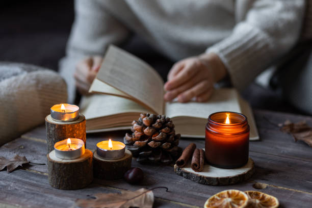 istock Autumn cozy home composition with hot chocolate with marshmallow and candles. Aromatherapy on a grey fall morning, atmosphere of cosiness and relax. Wooden background, books, close up. Girl reading a book 1449868910