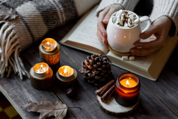 istock Autumn cozy home composition with hot chocolate with marshmallow and candles. Aromatherapy on a grey fall morning, atmosphere of cosiness and relax. Wooden background, books, close up. 1449868928