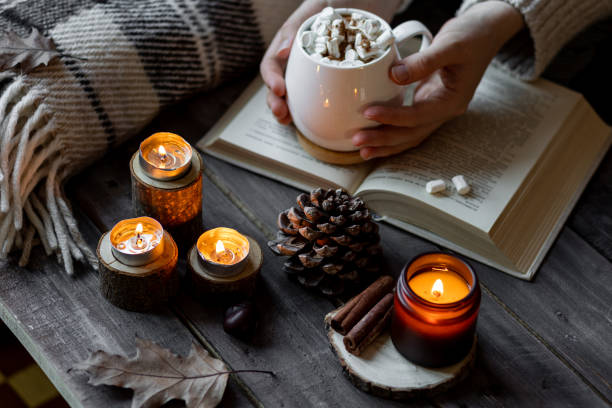 istock Autumn cozy home composition with hot chocolate with marshmallow and candles. Aromatherapy on a grey fall morning, atmosphere of cosiness and relax. Wooden background, books, close up. 1449868934