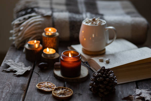 istock Autumn cozy home composition with hot chocolate with marshmallow and candles. Aromatherapy on a grey fall morning, atmosphere of cosiness and relax. Wooden background, books, close up. 1449868941
