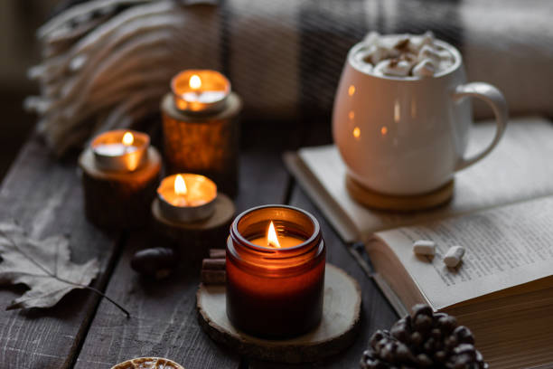 istock Autumn cozy home composition with hot chocolate with marshmallow and candles. Aromatherapy on a grey fall morning, atmosphere of cosiness and relax. Wooden background, books, close up. 1449868944
