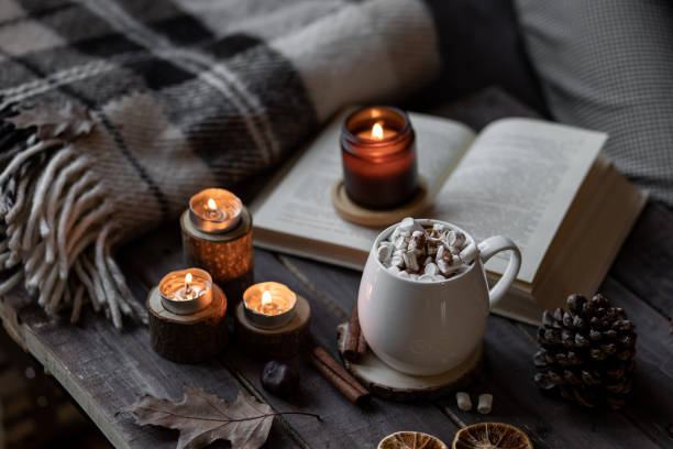 istock Autumn cozy home composition with hot chocolate with marshmallow and candles. Aromatherapy on a grey fall morning, atmosphere of cosiness and relax. Wooden background, books, close up. 1449868961