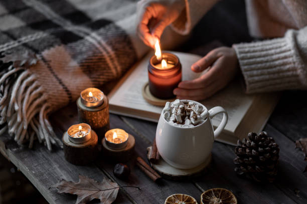 istock Autumn cozy home composition with hot chocolate with marshmallow and candles. Aromatherapy on a grey fall morning, atmosphere of cosiness and relax. Wooden background, books, close up. 1449868968