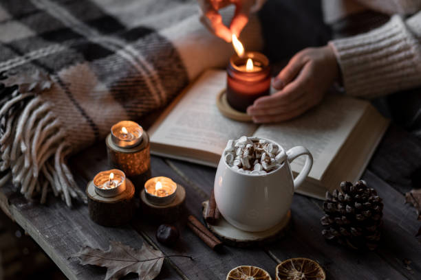 istock Cozy autumn or winter composition with aromatic candle, wool sweater, book. Aromatherapy, home atmosphere of cosiness and relax. Wooden background close up. 1449868972