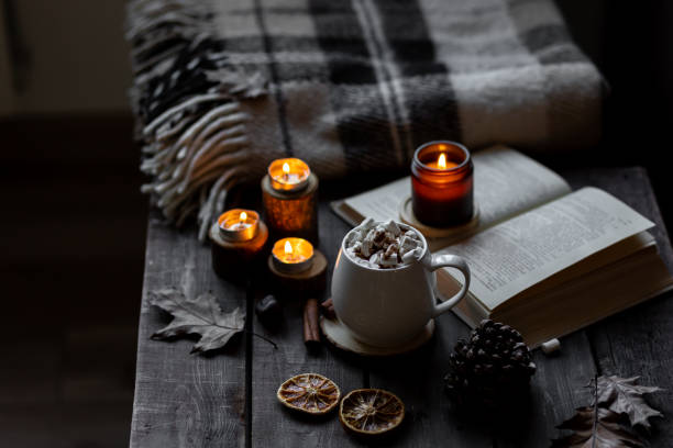 istock Cozy autumn or winter composition with aromatic candle, wool sweater, book. Aromatherapy, home atmosphere of cosiness and relax. Wooden background close up. 1449868985