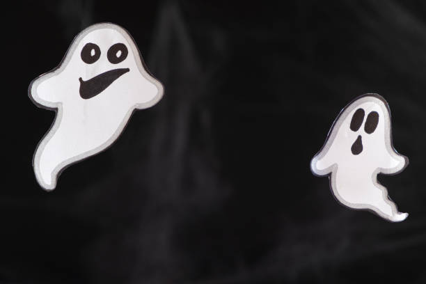 istock Two merry ghosts with faces fly and smile on a black background with a web. Halloween card, a place for text 1449871719