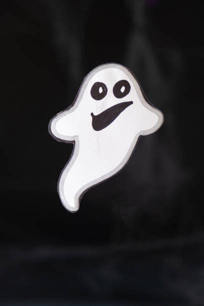 istock A cheerful white ghost with a face smiles and flies on a black background with a web. 1449871720