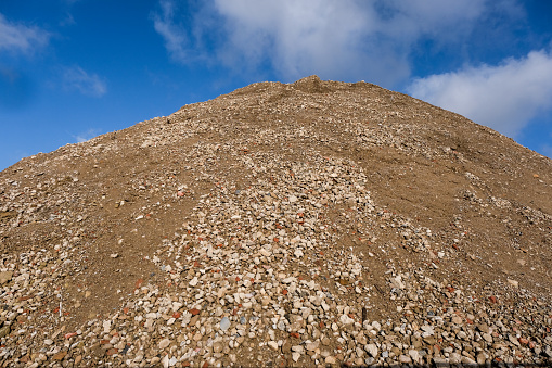 Construction site concept: A large pile of crushed stone and earth for commercial use and blue sky