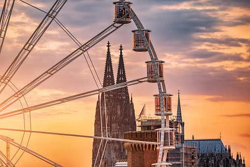 Ferris wheel in Cologne, Germany with a view of the main architectural sight of the city - Koln Cathedral at sunset