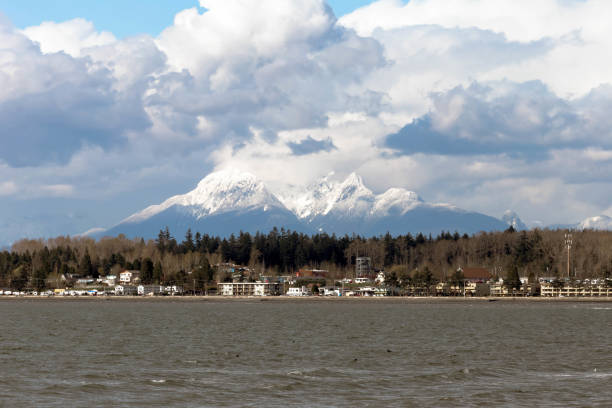 Panoramic view of snow-capped Mount Baker with puffy white clouds and still water of early spring. Wide view of Blaine, Washington, with snow capped Mount Baker and large puffy white clouds and calm water on a beautiful spring day blaine washington stock pictures, royalty-free photos & images