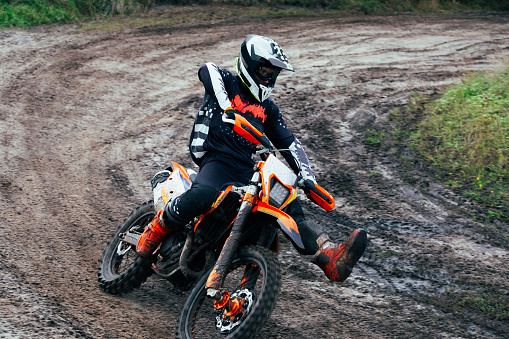 Motocross enduro rider in action accelerating the motorbike after the corner on dirt race track. Extreme off-road race. Hard enduro motorbike. Sky on background