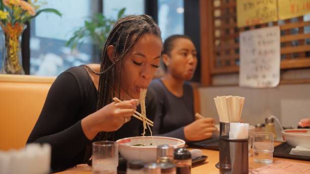 group of multi-racial group of friends tourists enjoying experiencing and having japanese food ramen in ramen shop - japanese culture japan japanese ethnicity asian and indian ethnicities imagens e fotografias de stock