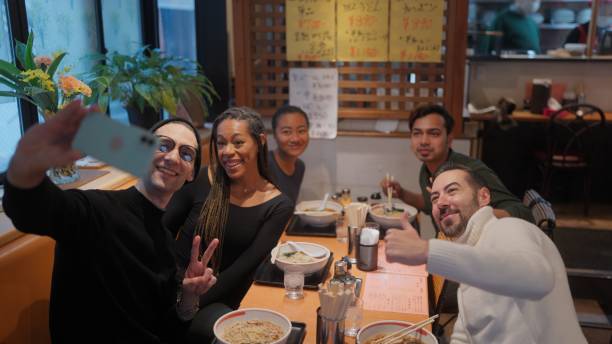 group of multi-racial group of friends tourists enjoying experiencing and having japanese food ramen in ramen shop - japanese culture japan japanese ethnicity asian and indian ethnicities imagens e fotografias de stock