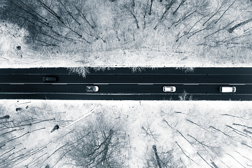 Aerial images of cars driving in snow covered frozen forest.