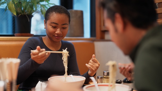 Two multi-racial friends tourists are enjoying eating ramen during their travel.