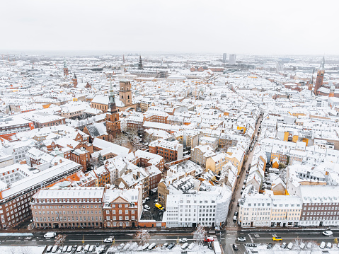 Cityscape with contemporary office buildings and residential flats in central Copenhagen covered in snow during winter. The view takes you across Nørreport Station with the yellow, public busses toward the Cathedral \