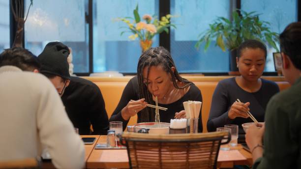 group of multi-racial group of friends tourists enjoying experiencing and having japanese food ramen in ramen shop - japanese culture japan japanese ethnicity asian and indian ethnicities imagens e fotografias de stock