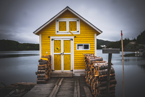Yellow wharf by the water with fire wood stack