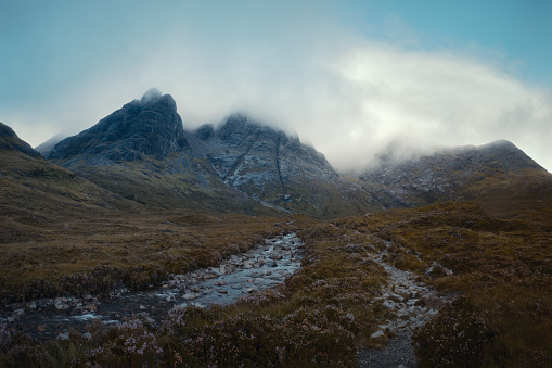 The morning panorama of the river and the footpath leading to the cloud-covered mountain peaks. Scenic summer landscape with river in the morning. Bla Bheinn, Isle of Skye, Scottish Highlands, UK.