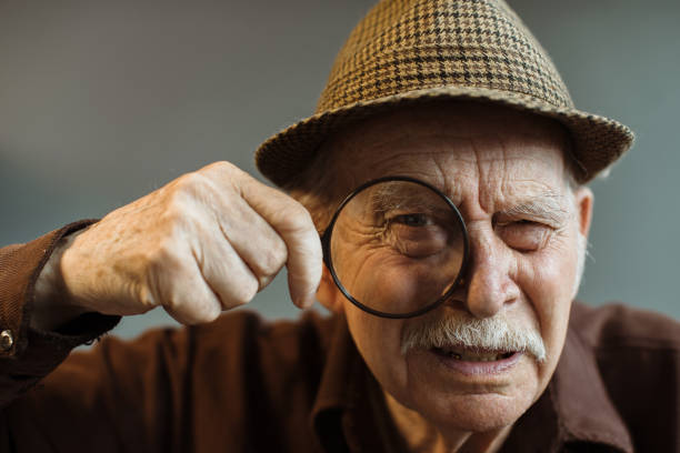 istock An old man looks at the camera through a magnifying glass. 1449891569