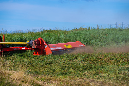 Gothenburg, Sweden - september 06 2022: Tractor cutting the grass in a field at summer.