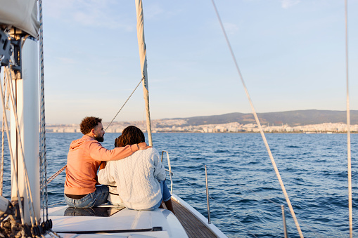 Parents And Teen Daughter Sitting Together On Sailboat Deck Hugging Enjoying Sea Trip. Luxury vacation at sea.