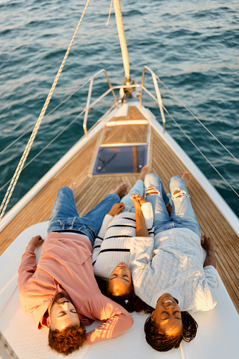 A family lies on the deck of a sailboat and enjoys the sea breeze. Luxury vacation at sea.